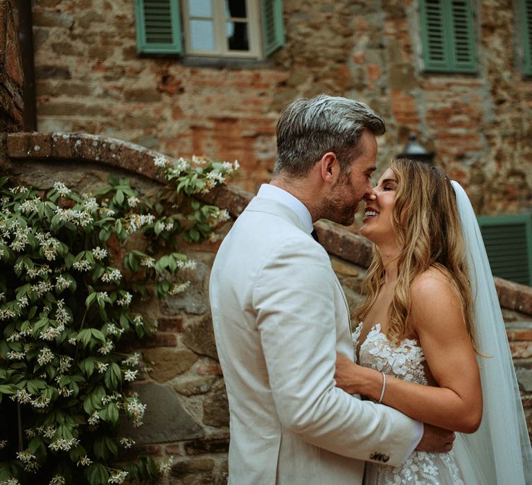 Bride and groom share a kiss in front of italian villa at destination wedding in Tuscany