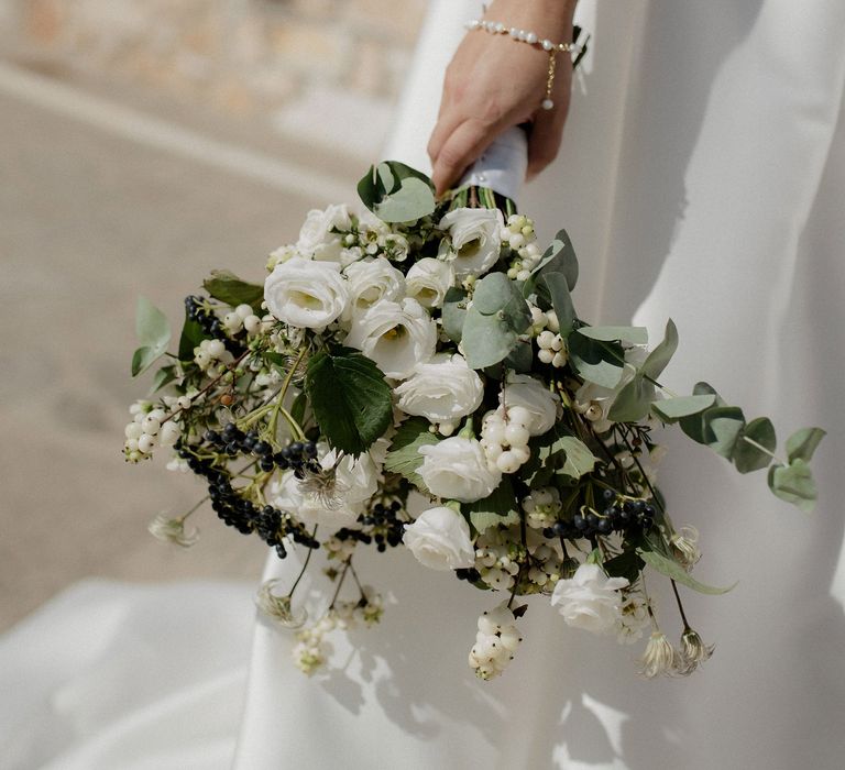 Bridal bouquet featuring white berries, italian ranunculus and eucalyptus at Greek destination wedding