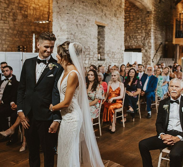 The bride and groom smile lovingly at each other for their civil ceremony in a barn at Priston Mill 