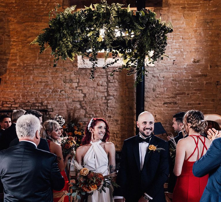 Bride with red hair clipped to the side with white hair accessory walks down the aisle with the groom as a married couple after the civil ceremony 