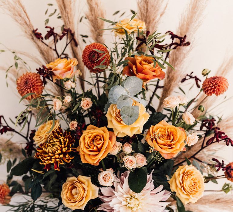 Orange and brown dahlias, roses, cafe au lait dahlias and more in wedding flower arrangement 