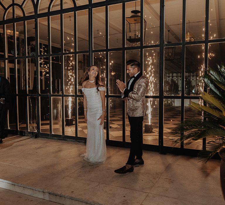 Bride in sparkly off the shoulder reception dress dancing with groom in gold blazer with black lining, black bowtie and black suit trousers 