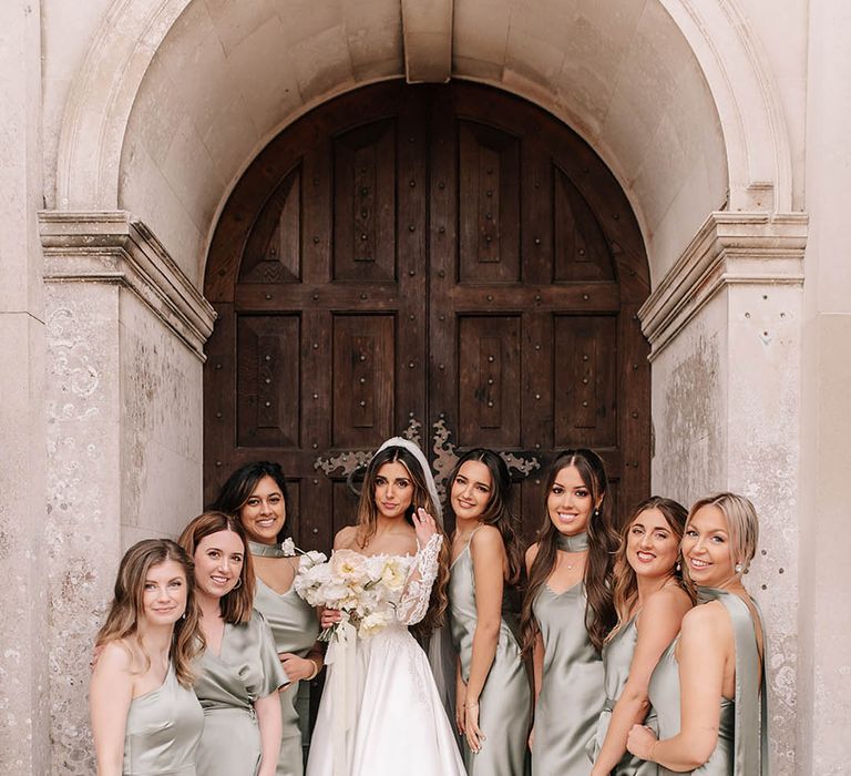 Bridal party in green mismatched bridesmaid dresses with the bride in lace long sleeve wedding dress 