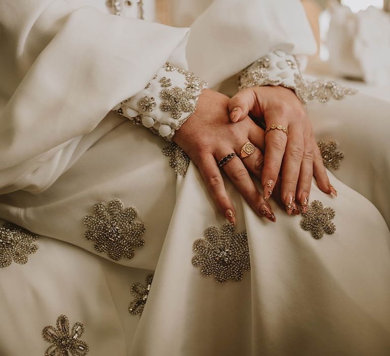 Bride wearing gold 3D flower wedding nails with gold rings and sparkly jumpsuit by Bowen Dryden 