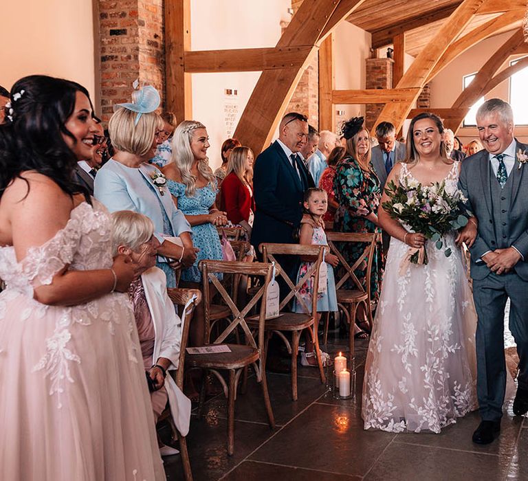 Father of the bride in three piece grey suit walking down the aisle with the bride in a lace wedding dress at The Oakwood at Ryther 