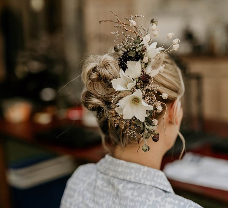 Bride with blonde hair in a slick updo wearing a white flower hair accessory 