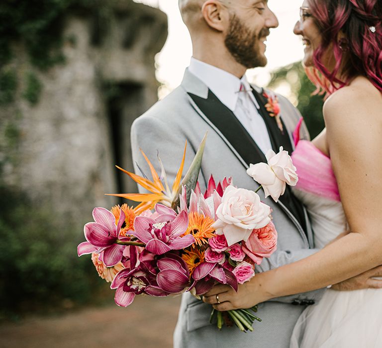 bride in a strapless wedding dress with pink bow holding a pink orchid and rose wedding bouquet