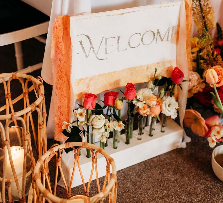 Wooden welcome wedding sign with orange frayed ribbon and test tube vase holders with garden roses and Iceland poppies 