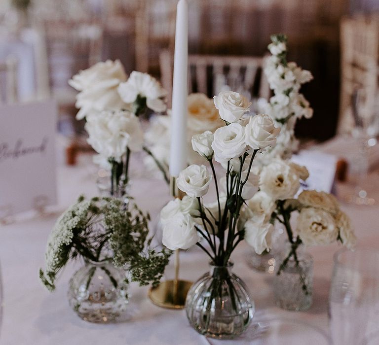 Wedding flower table decorations with bud vases, white wedding flowers, and taper candles 