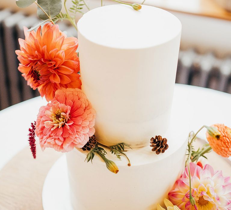 Two tier white iced wedding cake with colourful bright wedding flower decor 