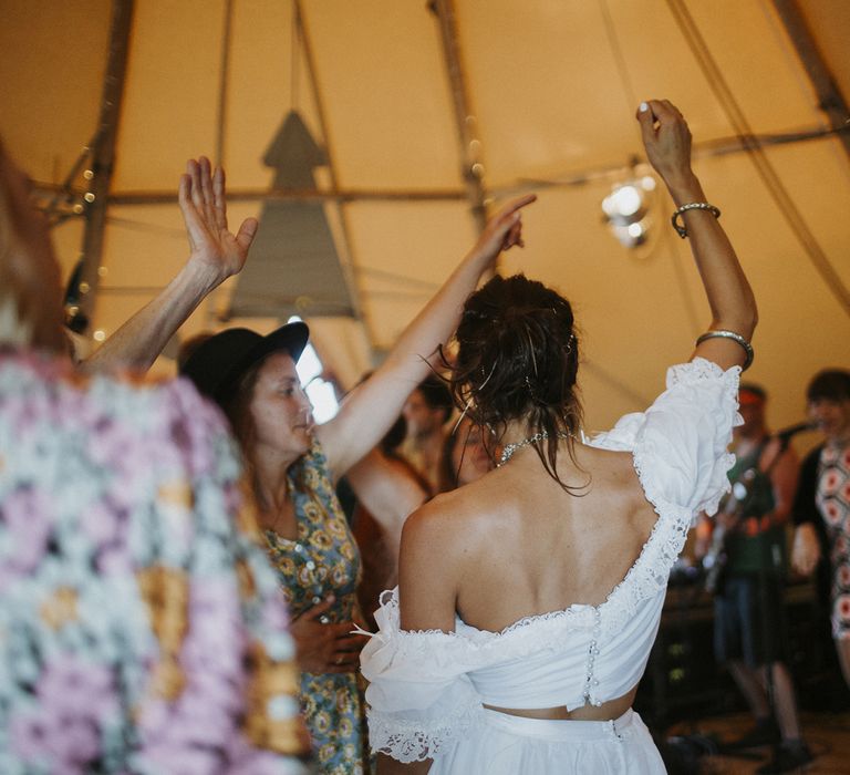 Bride dancing at tipi wedding in a ruffle off-the-shoulder crop top and gold bangle wedidng jewellery