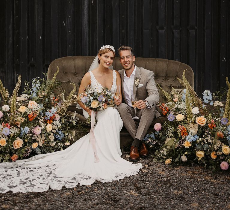 Bride in Justin Alexander wedding dress sitting with the groom in grey wedding suit 