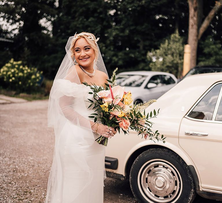 The bride carries a tropical wedding bouquet on her way to the church ceremony 