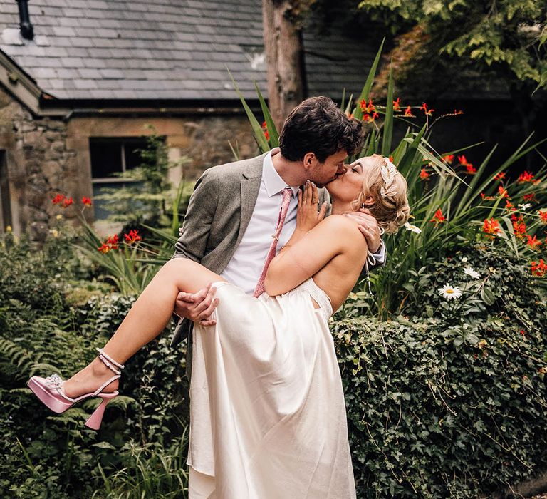 Bride wearing Mach & Mach pink wedding shoes kissing the groom 