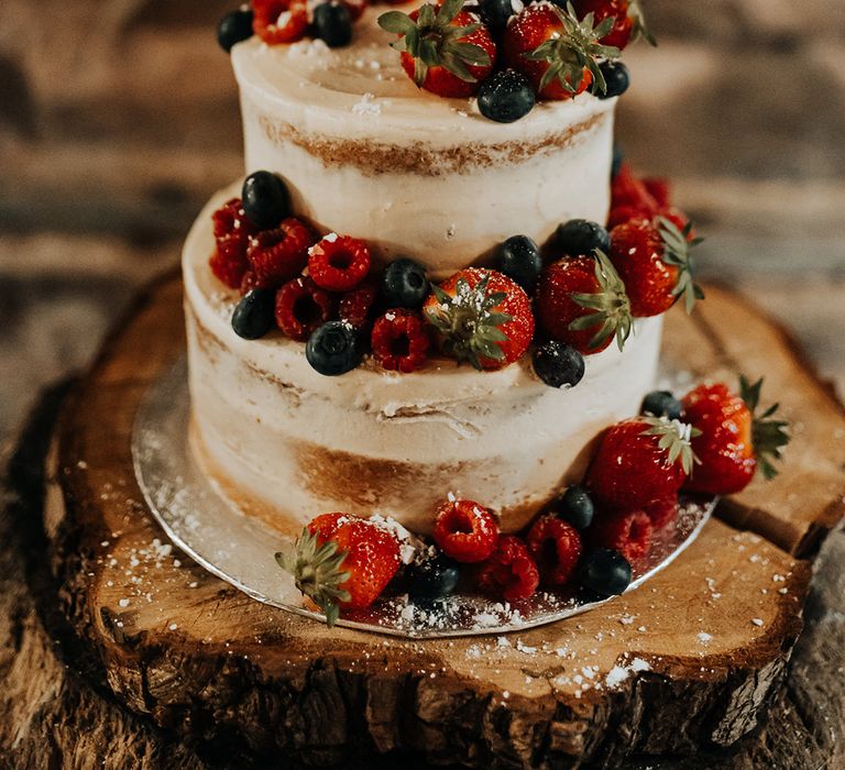 Semi naked two tier wedding cake decorated with summer berries 