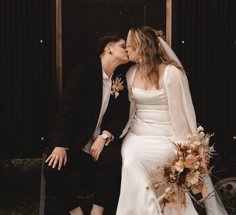 Lesbian wedding with two brides sharing a romantic kiss at The Giraffe Shed with industrial vibe 