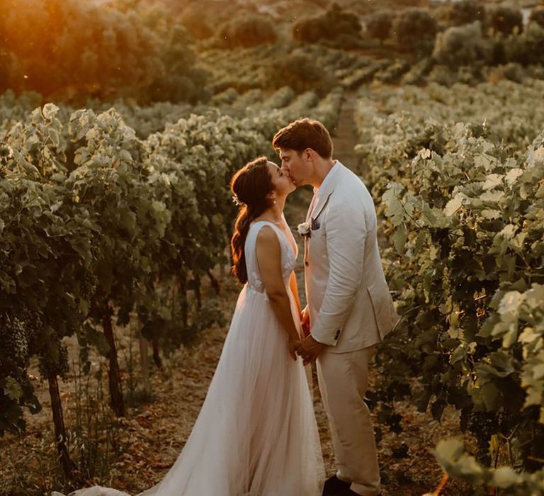 Bride and groom in a vineyard for their Crete wedding sharing a kiss during golden hour 