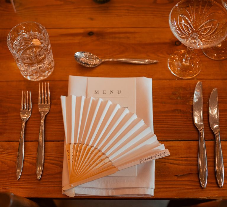 Simple and minimalist wedding place setting with fan wedding favours 