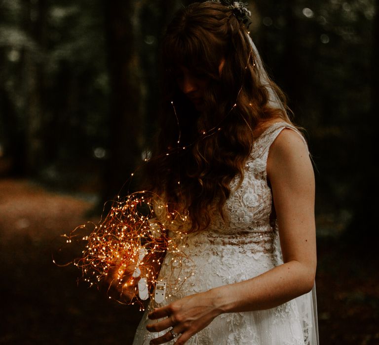 Bride in pearl detailed wedding dress draped with string fairy lights 