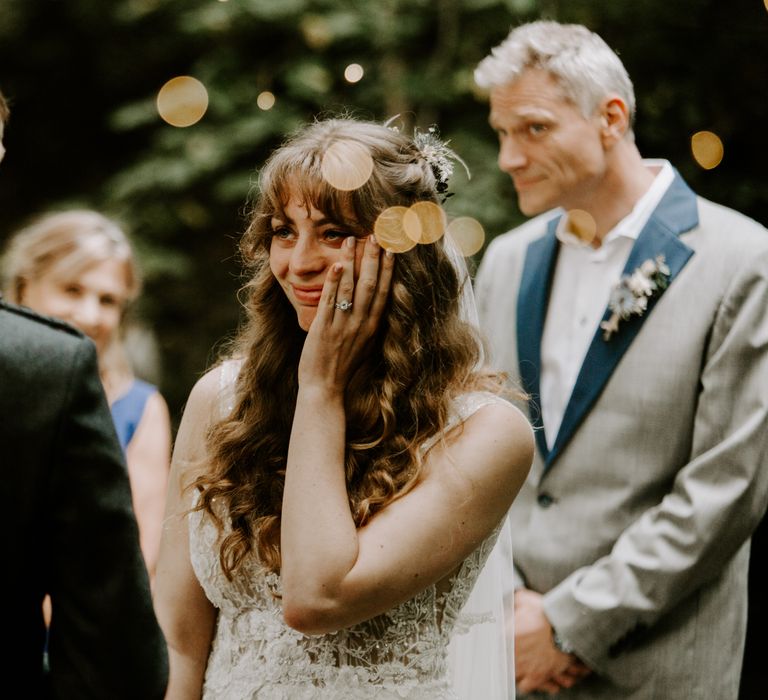 Bride looks adoringly at groom in sparkly floral wedding dress and long curly hair