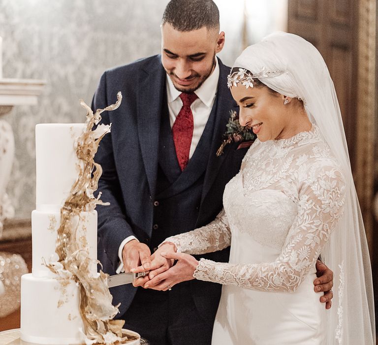 Bride and groom cutting the wedding cake with gold decor 