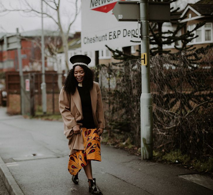 Bride in black dress with African print, Ndebele necklace, Zulu hat, boots and overcoat walking to her Lobola ceremony 