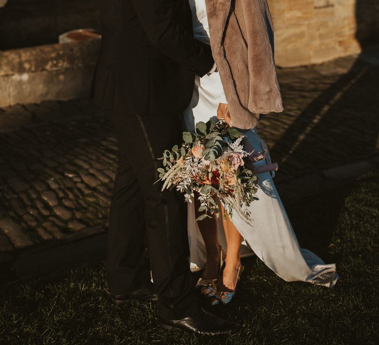 Groom kisses bride whilst bride wears fur jacket 