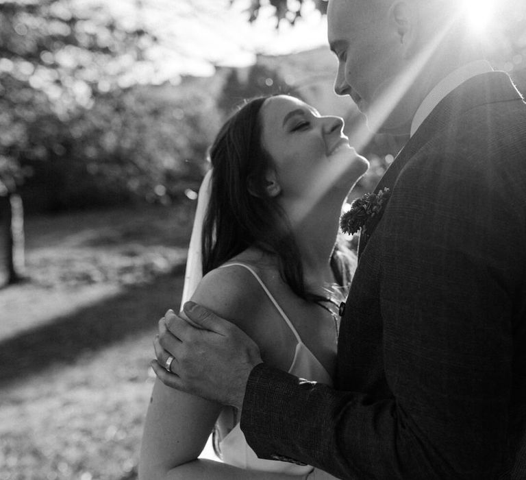 Black and white wedding day photography bride and groom smiling with natural sun light shinning on them 