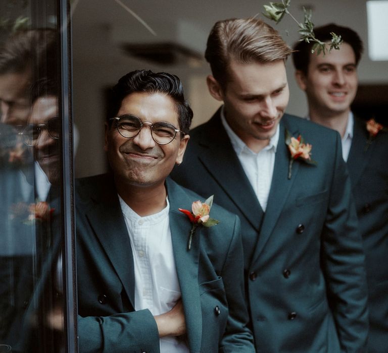 Groomsmen in white shirts, teal suits and orange buttonhole flowers 