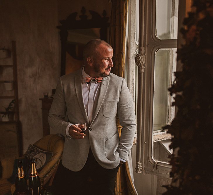 Groom in a grey blazer and pink feather bow tie with chain | The Springles 