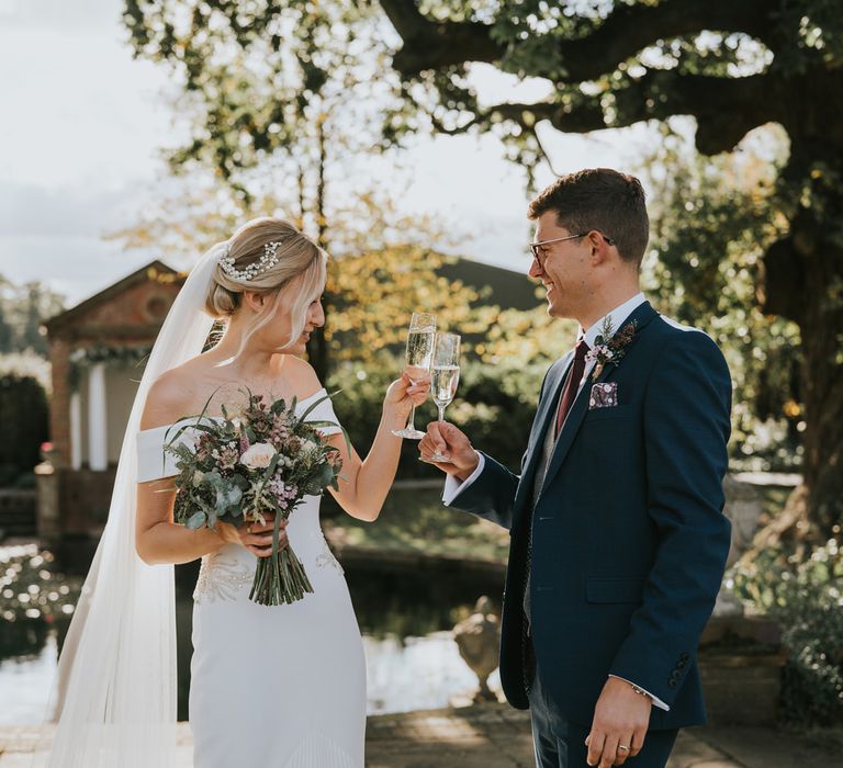 Bride & groom cheers outdoors with glasses of champagne 