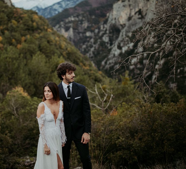 The bride and groom pose next to each other in the green hills of Greece