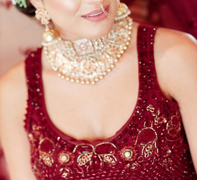 Bride wears golden jewellery and burgundy outfit