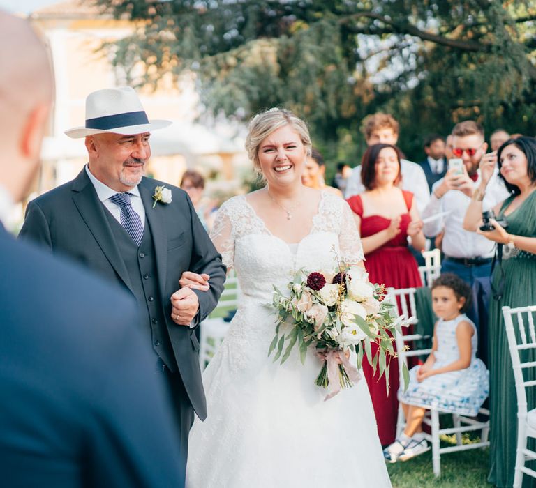 The bride reaching the end of the aisle with her father, smiling at the groom