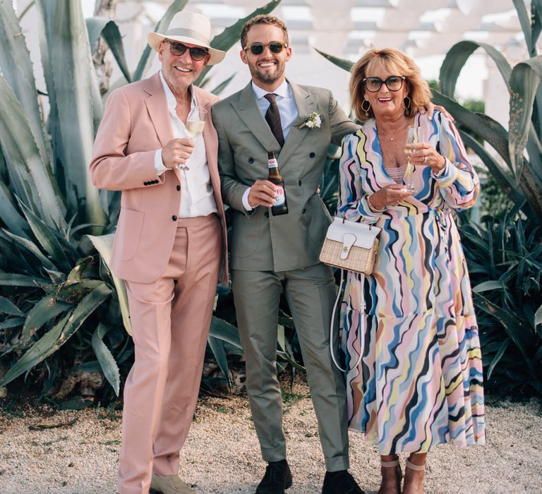 The groom and his parents standing in front of huge succulent plants