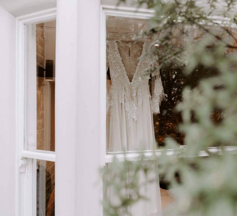 Lace bridal dress hanging in window