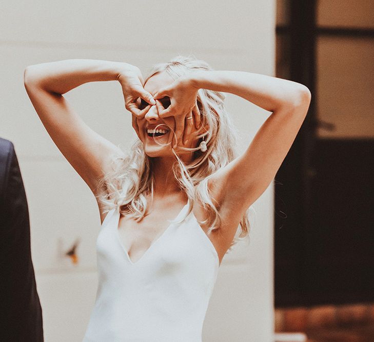 Bride in a Dove Grace Loves Lace minimalist wedding dress pulling funny faces at her groom 