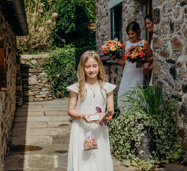 Bridesmaid walks outdoors whilst holding confetti and hair in loose curls with headband