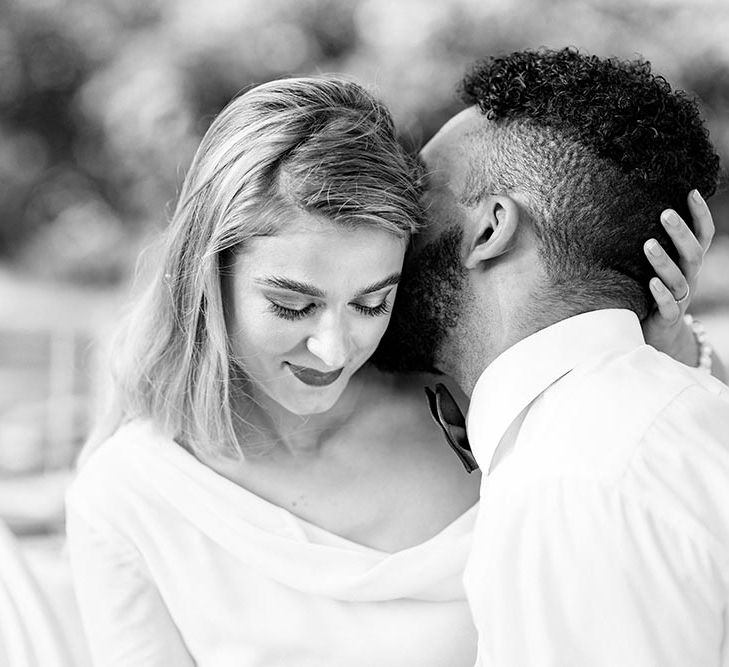 Black and white intimate bride and groom portrait with the groom kissing his brides neck 