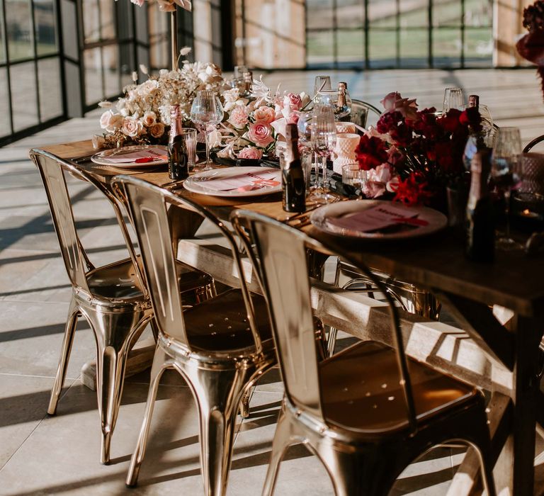 Intimate wedding table decor at Botley Hill Barn with orchid and rose flowers, industrial chairs and miniature bottles of Moet & Chandon 