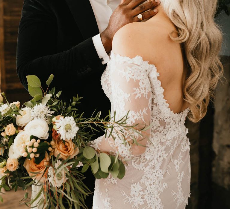 Bride and groom kissing at micro wedding ceremony, the bride's off the shoulder wedding dress has a low back detail