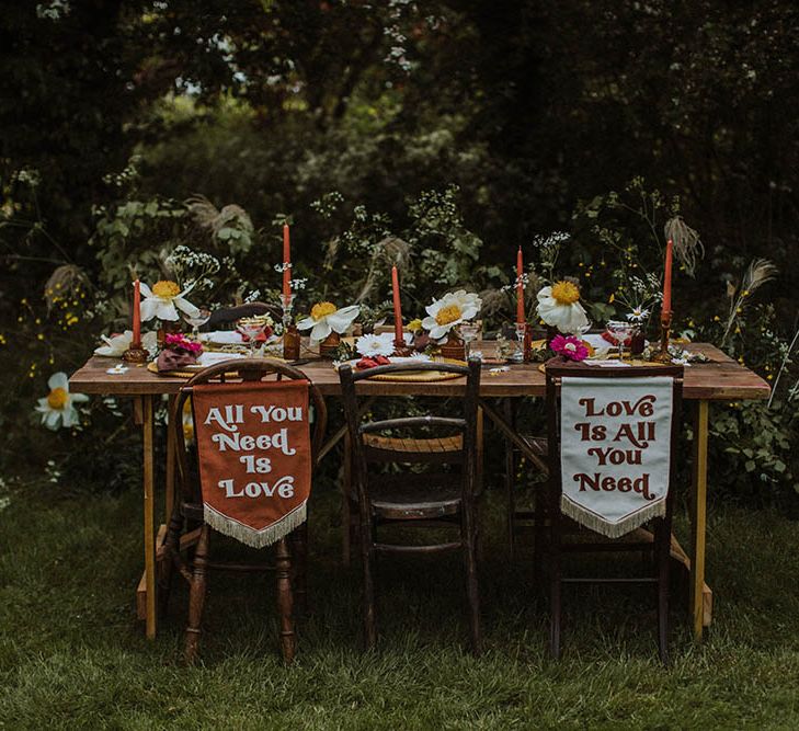 Outdoor wedding reception with fabric chair back signs, wild flowers and colourful decor 