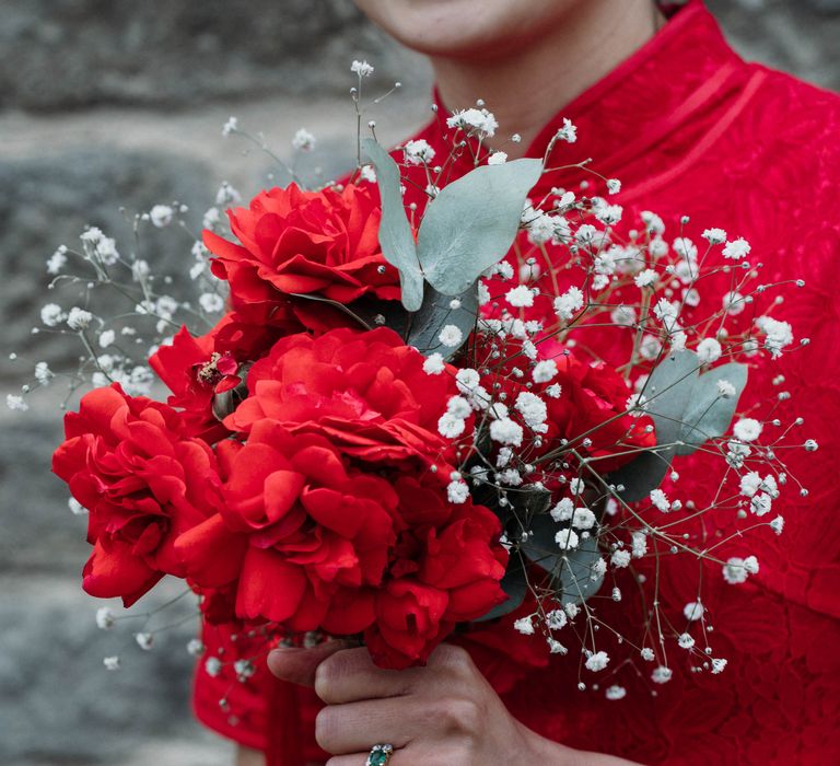 Bride holds red roses whilst wearing traditional Chinese dress for Tea Ceremony