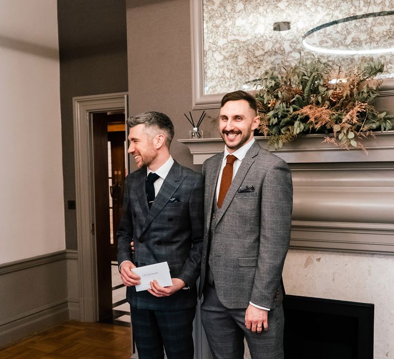 Grooms during wedding ceremony in front of fireplace within the Old Marylebone Town Hall