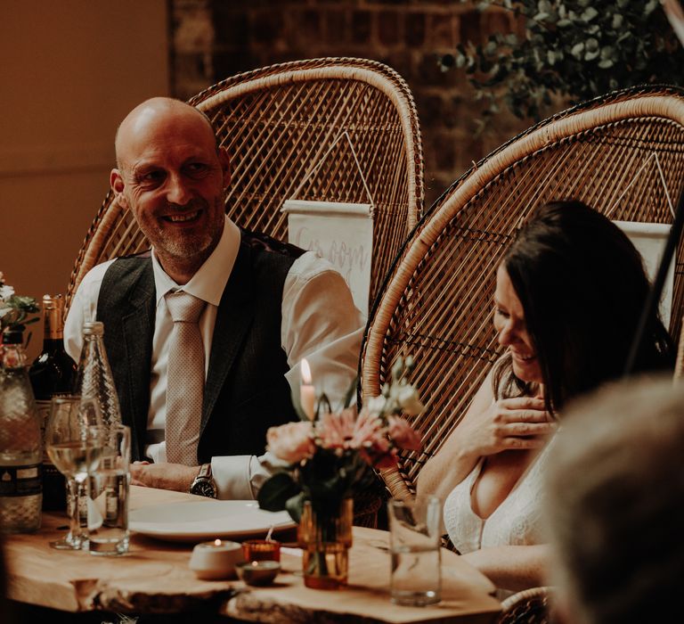 Bride and groom sit on peacock chairs