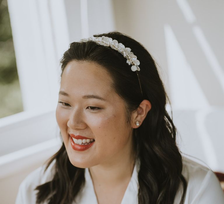 Beautiful East Asian bride with flower appliqué headband and coral lipstick