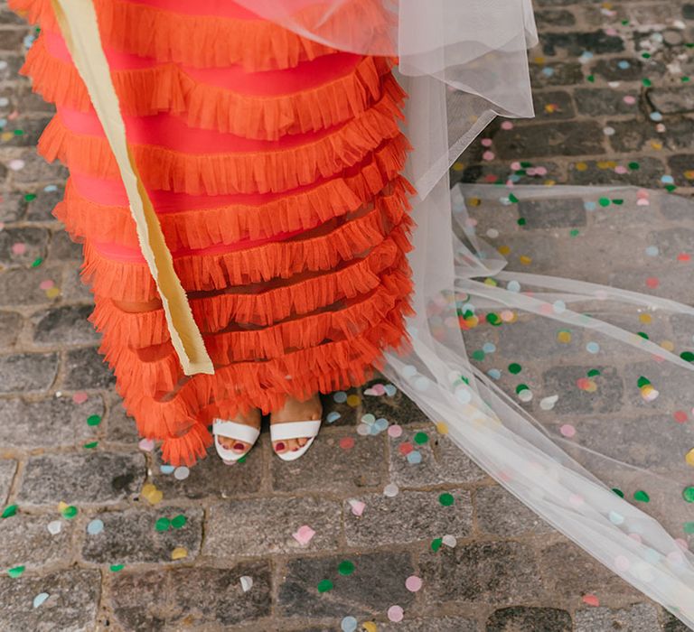 Bride in coral wedding dress with white shoes and cathedral length veil