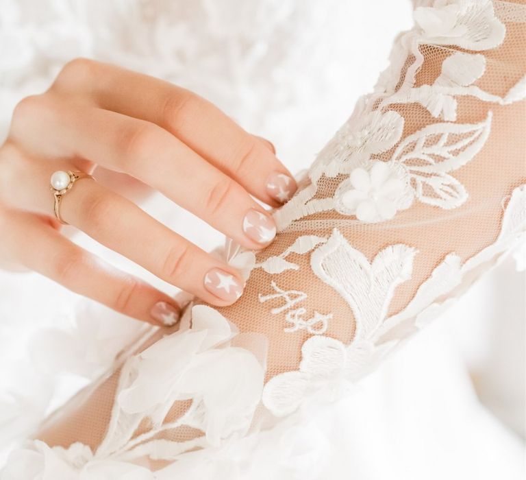 Bride wears peal engagement ring with gold band and has white stars on her nails | Carn Patrick Photography