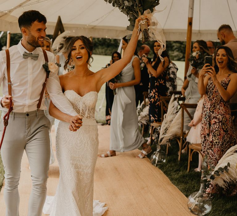 Bride & groom celebrate as they walk through marquee on their wedding day | Mark Bamforth Photography