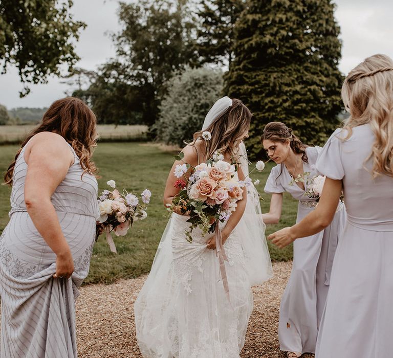 Bride holds floral bouquet as her bridesmaids stand around her